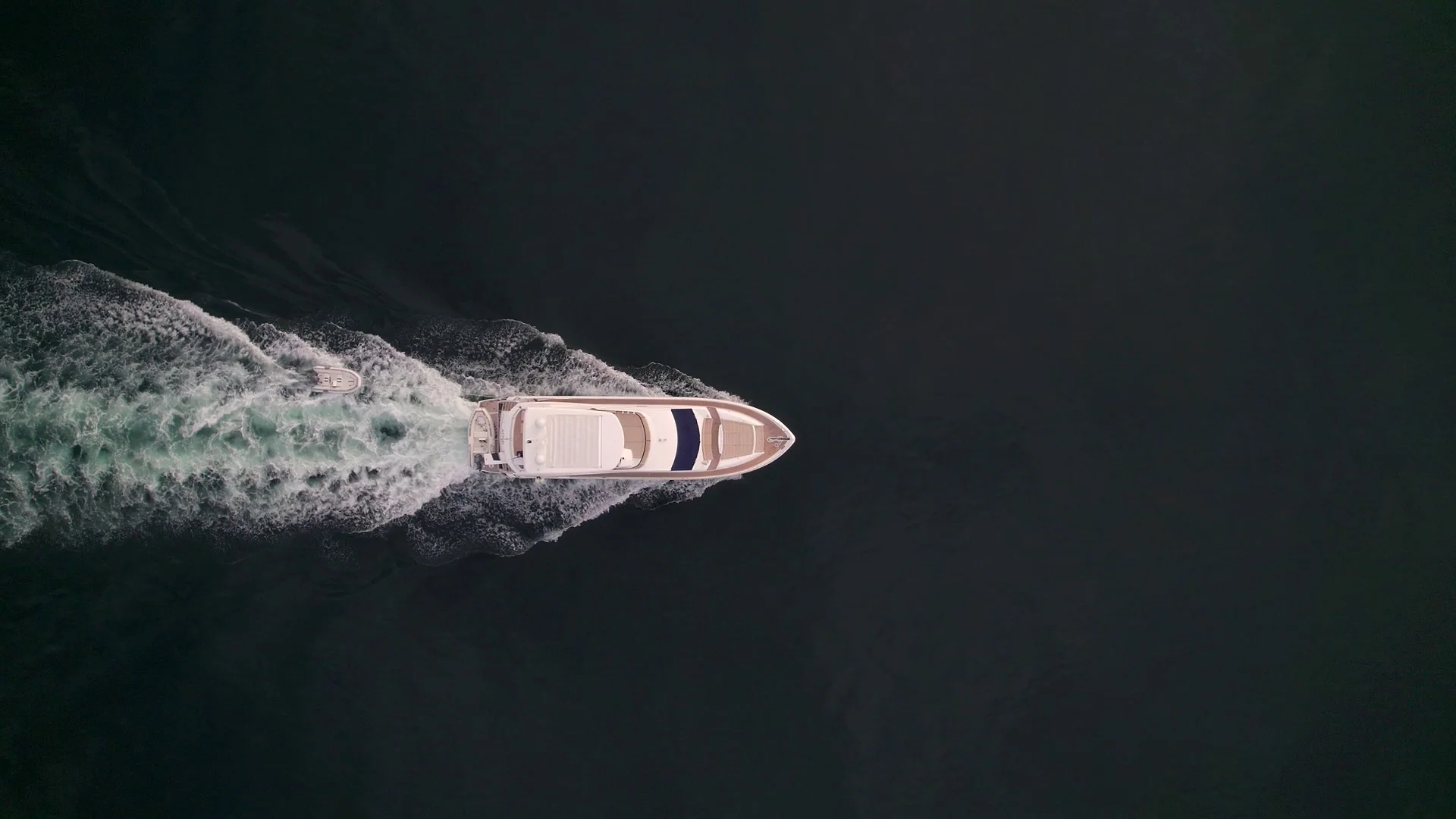 A motor yacht underway on dark open water, seen from above