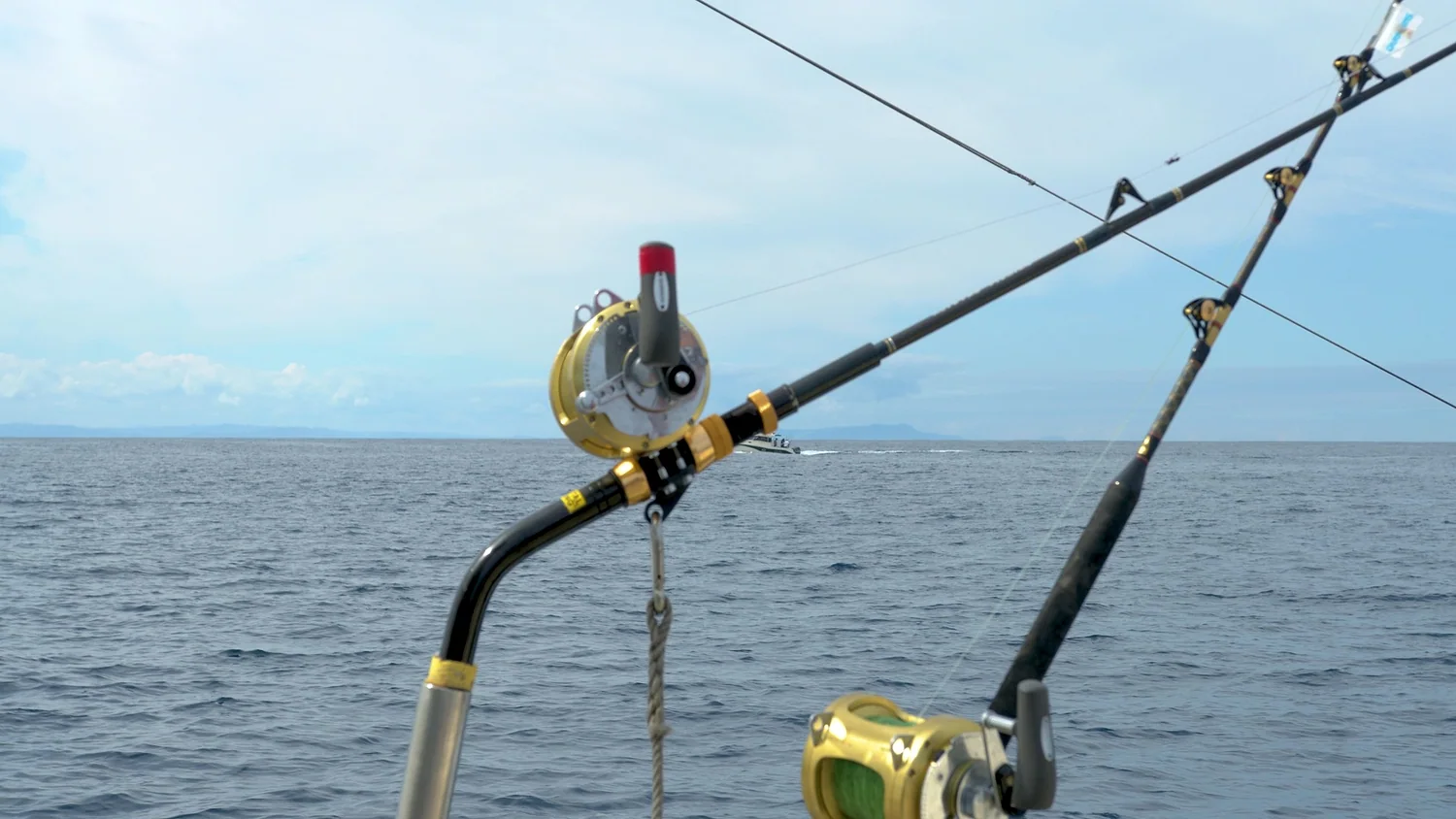 Two gold lever drag conventional reels set in rod holders on a trolling boat
