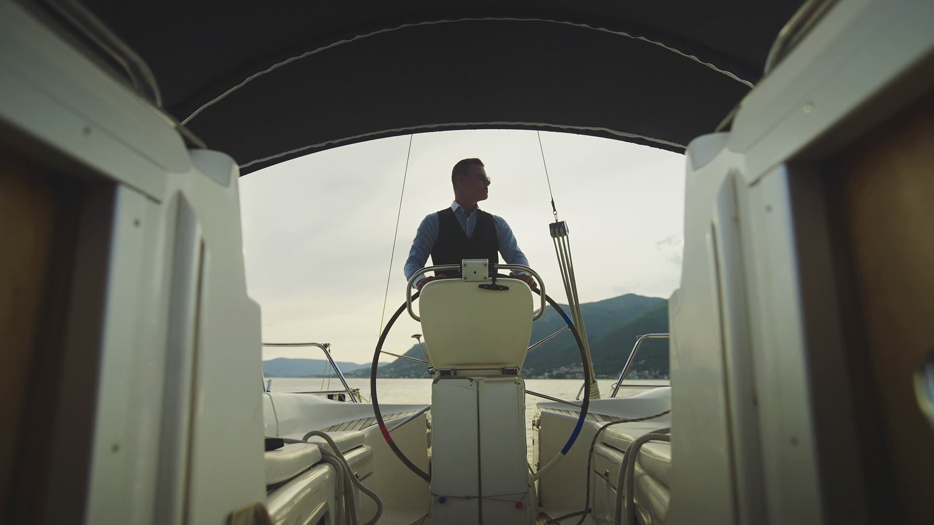 A skipper at the wheel of a sailing yacht