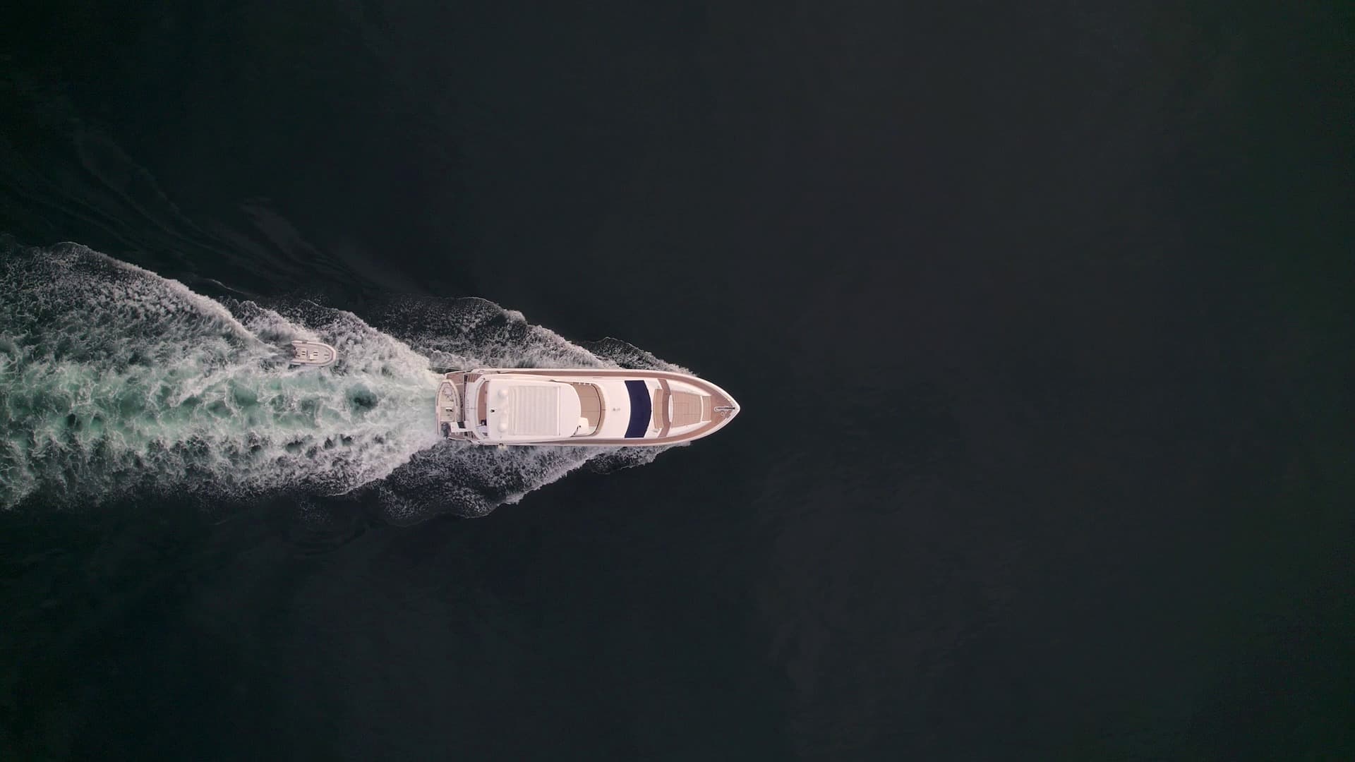 A motor yacht underway on dark open water, seen from above