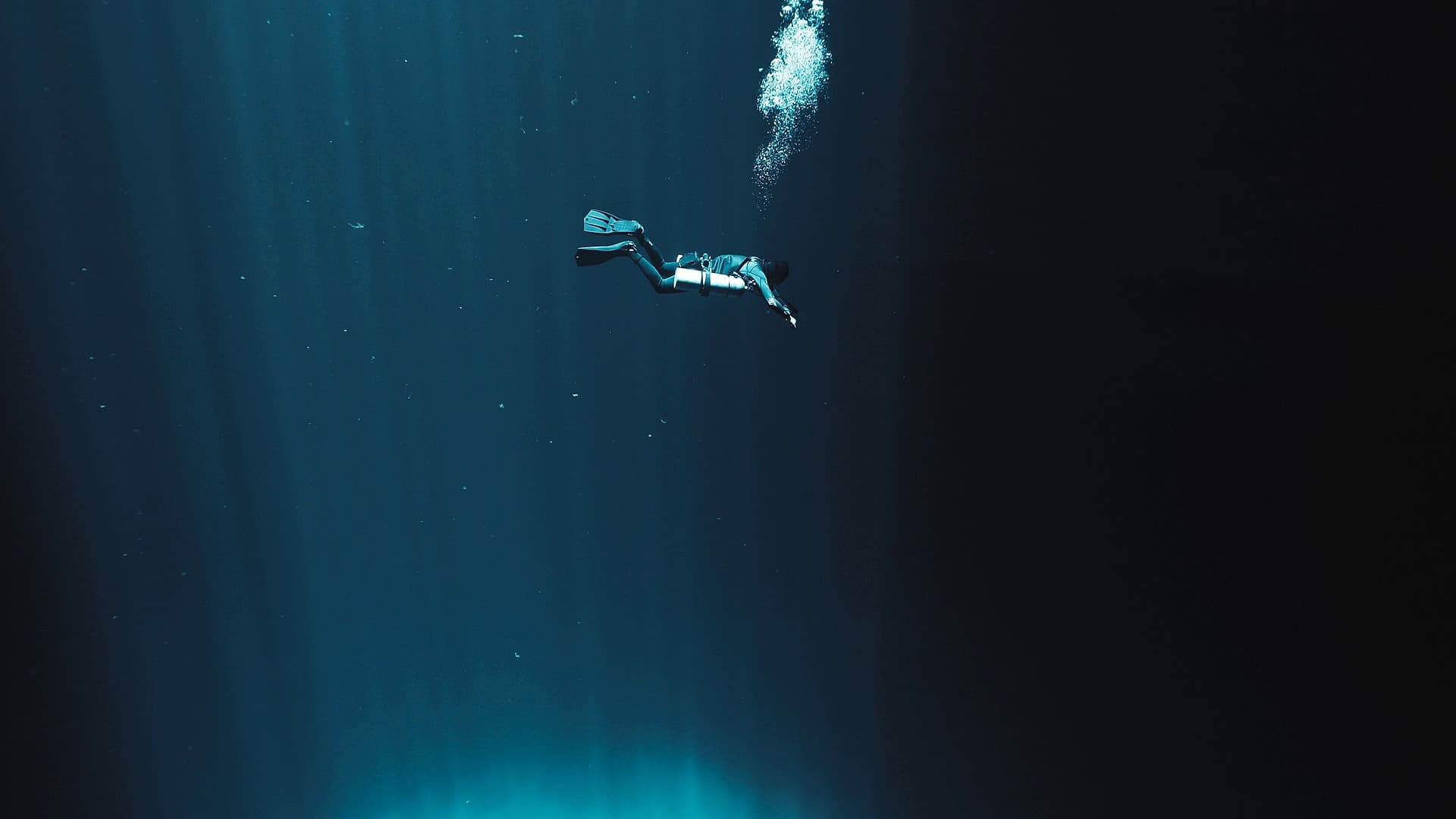 A single diver descending through open blue water